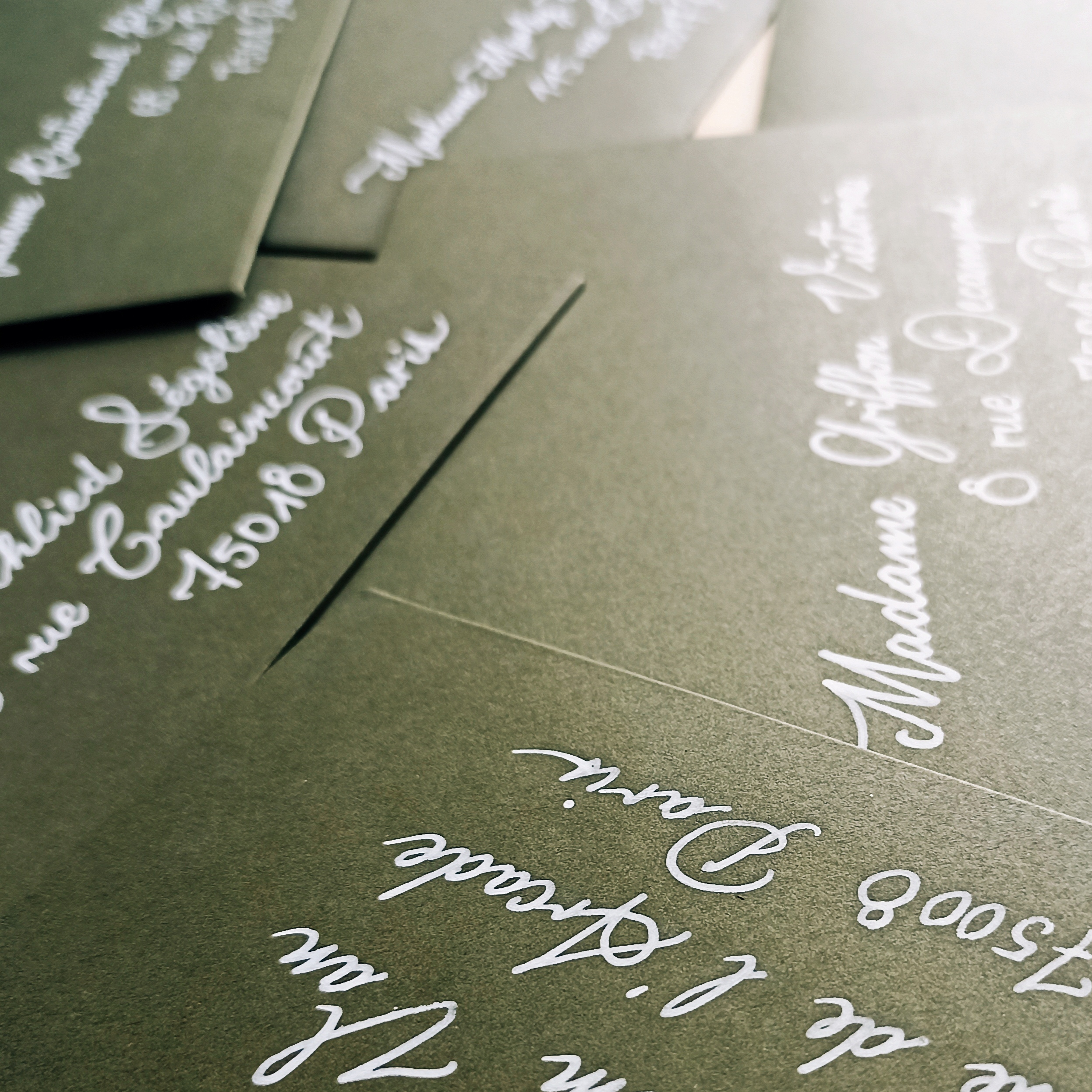 Enveloppes colorées calligraphiées au feutre et encre blanche.